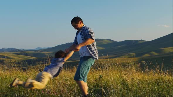 Father is holding his son and spinning around on scenic background