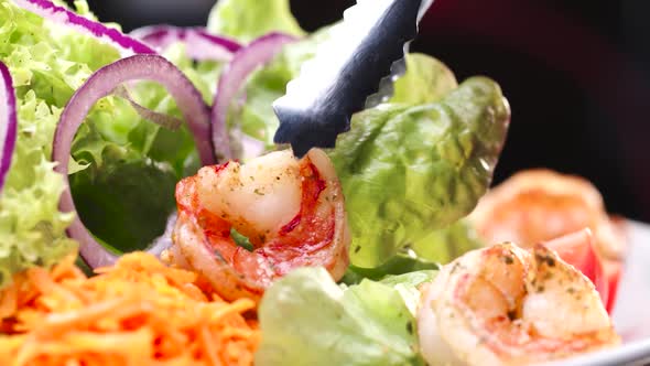 The Hand of the Chef in the Restaurant Lays the Shrimp on the Ready Salad. alt