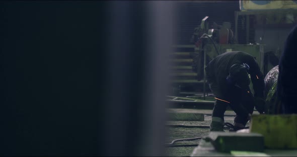 A Professional Worker in a Protective Mask Works with a Grinder in a Factory alt