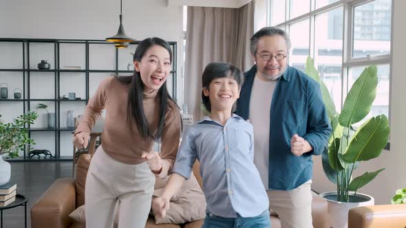 Happy asian family dancing together in the living room at home