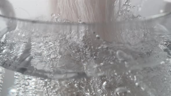 Camera follows cooking bean thread noodle in boiling water. Slow Motion. alt