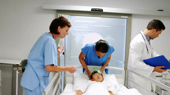 Doctors placing an oxygen mask and adjusting a iv drip to patient in emergency room alt