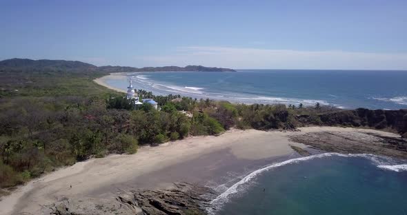Aerial drone view of the beach, rocks and tide pools in Guiones, Nosara, Costa Rica. alt