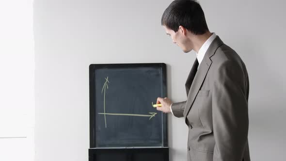 Creative Young Businessman in Suit Draws Charts on Board
