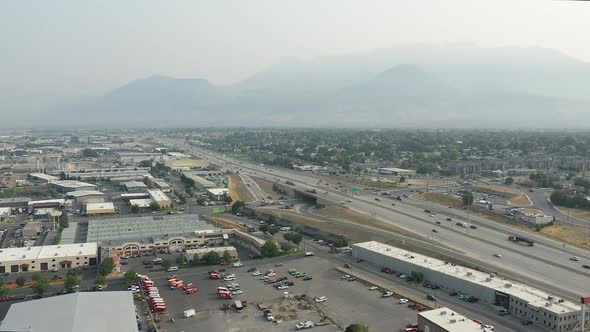 Aerial view rotating over industrial area next to freeway with smokey skies alt