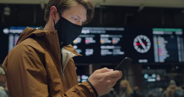 Young Man at Train Station or Airport in Face Mask alt