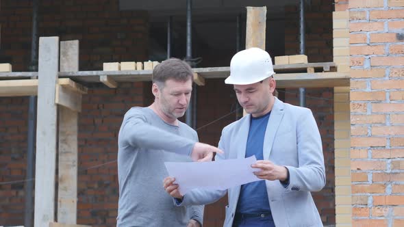 Against the Background of the Construction of Two People Discussing the Project for the Construction