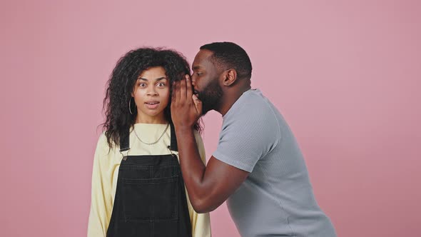 African American Man Coming to His Girlfriend and Whispering Secret to Her Ear Woman Feeling Shock alt