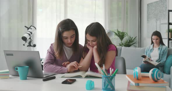 Girl helping her younger sister with homework, they are studying together