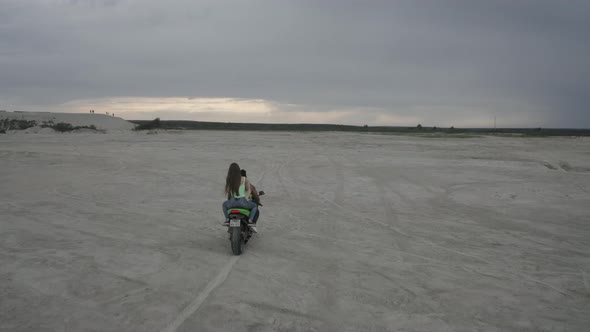 A Beautiful Young Couple Man and Woman are Riding on a Motorbike Together on the Beach During Sunset