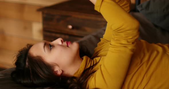 Woman using mobile phone on bed alt