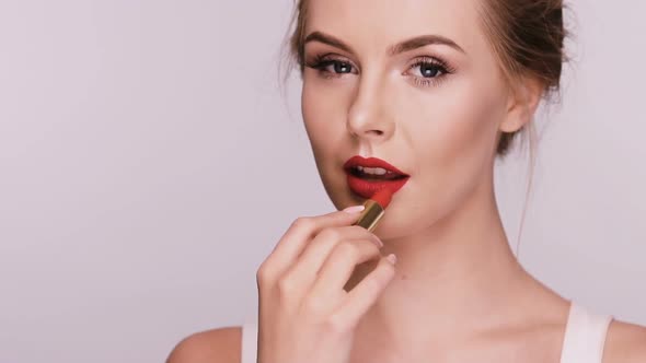 Beautiful Woman Applies Red Lipstick and Showing Heart with It alt