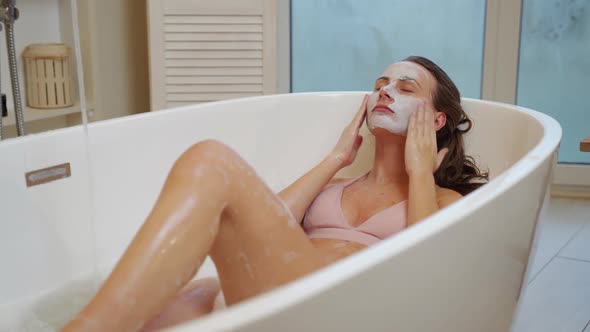Young Girl Applies a Facial Scrub to the Skin While Sitting in the Bathroom alt
