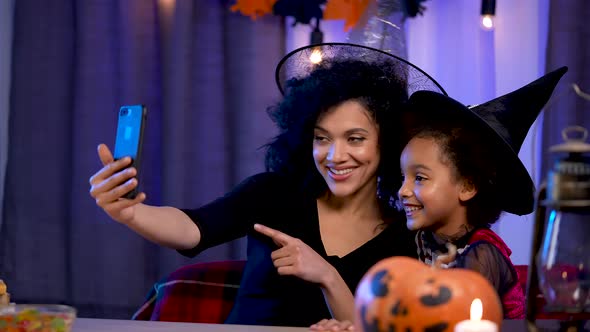 Little Girl and Young Woman African American in Witch Hat Communicate By Video Call Using a alt
