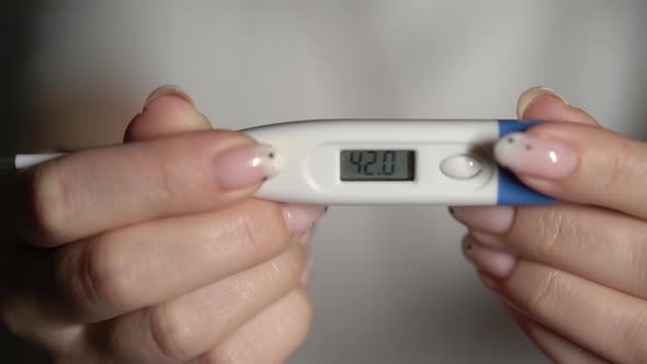 Woman Holds Thermometer in Hands to Measure Body Temperature