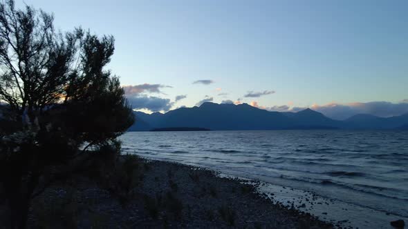 Small lake waves crashing on the rocky beach of Lake Te Anau in New Zealand the dusk alt