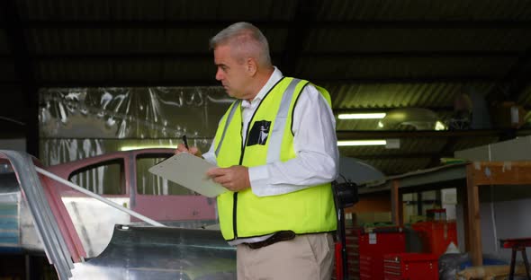 Male engineer writing on clipboard in hangar alt