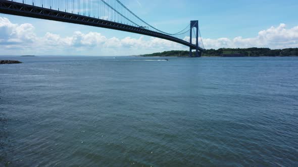 a low angle drone view of Lower New York Bay. The drone dolly in towards The Verazzano Bridge with a alt