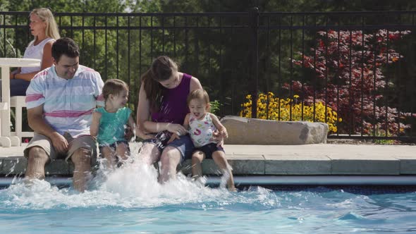 Family splashing feet in backyard pool