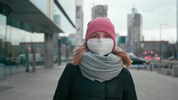 COVID-19 Coronavirus Pandemic, Woman in Surgical Face Mask Walks in City Street