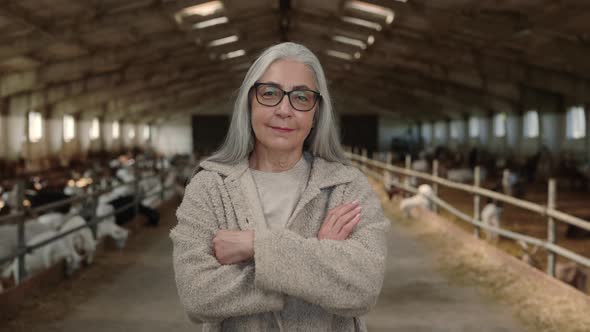 Farm Worker Posing with Crossed Arms at Ranch with Goats alt
