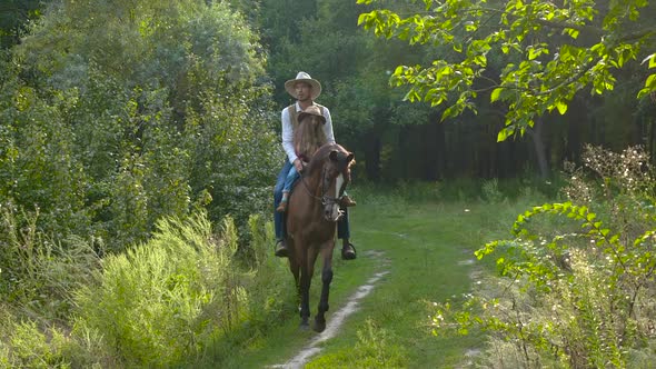 Cowboy and His Daughter on Horseback on a Forest Lawn alt