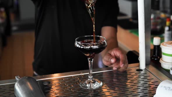 Black Manhattan being poured into a glass in slow motion. Rich brown tones are found in this shot fr alt