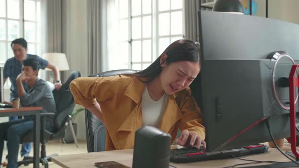 Asian Female Paining Her Back While Works On His Personal Computer In Office alt
