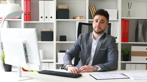 Young Businessman in Workplace Looking at Camera