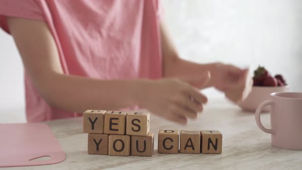 Motivating Quote Yes You Can On Table. Woman Makes A Joyful Positive Gesture With Her Hands alt