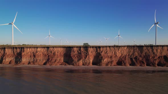 Windmills on a cliff above the sea, top view. Wind farm for wind energy.