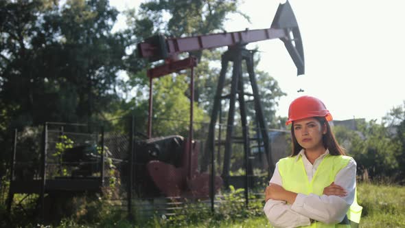 Portrait of Female Engineer Against Background of Oil Drilling Rig alt