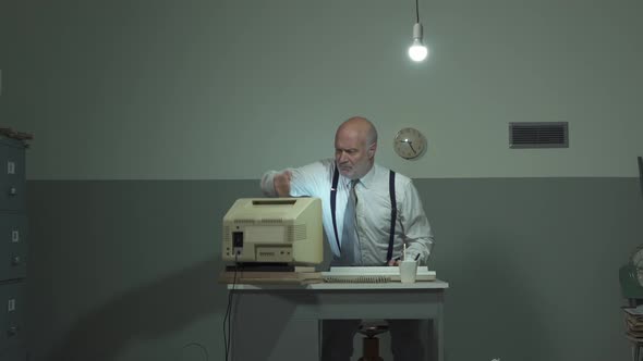 Angry businessman hitting his outdated computer