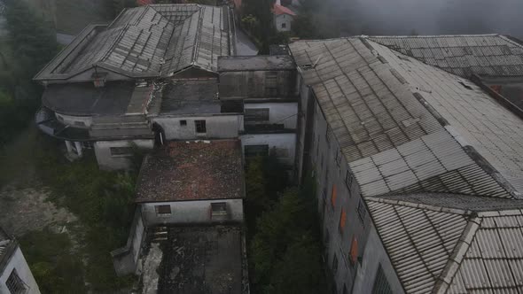 Drone flying over roof of Caramulo big Sanatorium old abandoned building on misty day, Portugal alt