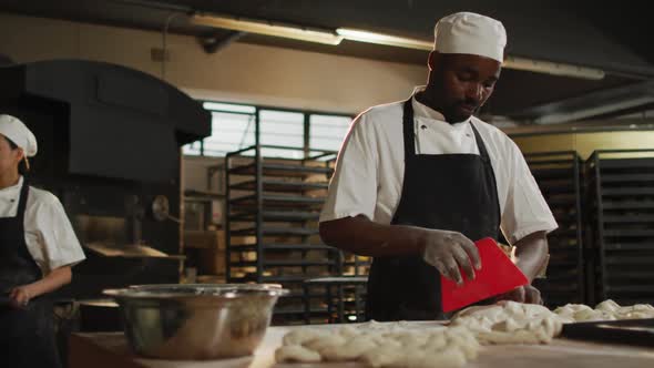 Animation of happy african american male baker cutting sourdough for bread alt