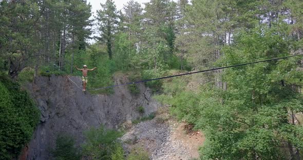 A man tries to balance and falls while slacklining on a tightrope alt