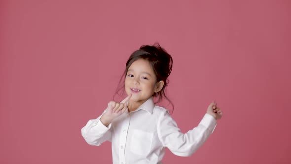 Little Child Girl in White Shirt Dancing on Pink Background