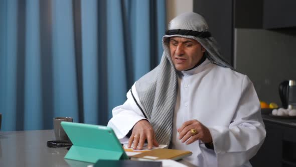 Troubled Irritated Middle Eastern Freelancer Hanging Up Phone Analyzing Paperwork in Home Office alt