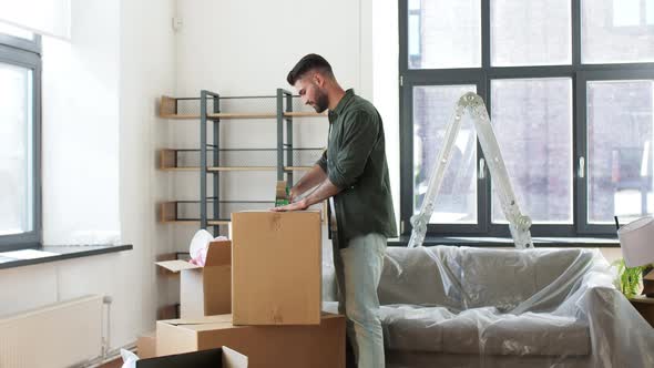 Man with Adhesive Tape Packing Box at Home alt