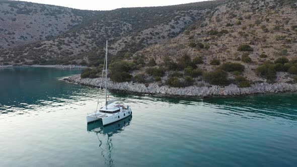 Catamaran and Sail Yachts Anchored at Bay on Deep Blue Sea Water on Sunrise alt