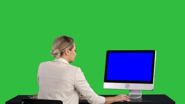 Woman Working Looking at Monitor at Office on A Green Screen alt