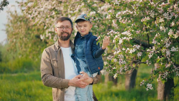 Portrait of a Happy Man with His Little Son in His Arms Standing in the Garden alt
