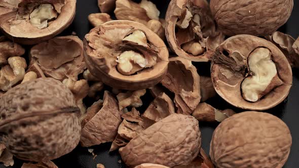 Lot of Walnuts in the Shell are Spinning on a Black Background alt