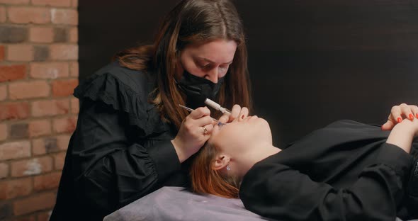 Lashmaker Does the Eyelash Lamination Procedure for the Client in the Beauty Salon Cosmetic Services alt