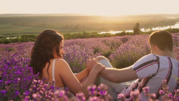 A Happy Couple of People in Love Have Fun Jostling Sitting in a Lavender Field
