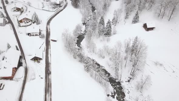 A car drives on a road, the drone tilts up to a nice panoramic view of a mountain. alt