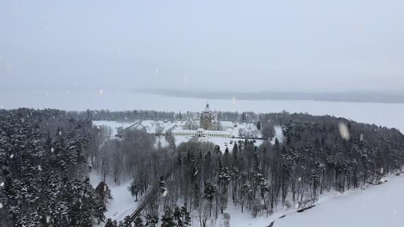 Snow-covered Pazaislis Monastery during snowfall, aerial flying towards view alt