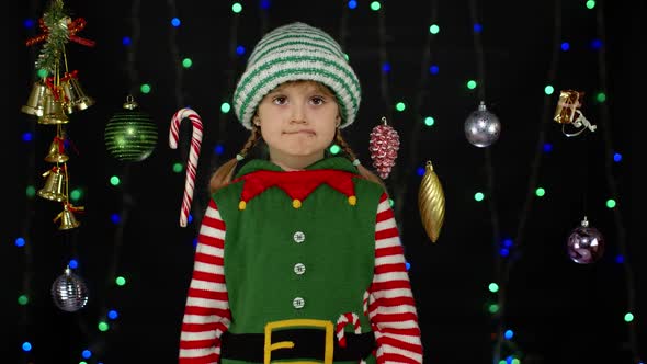 Shy Shamed Child Girl in Christmas Elf Santa Helper Costume Posing Looking Camera Making Funny Faces alt