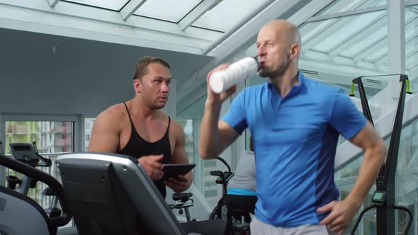 Trainer Controlling Progress of Middle-aged Man alt