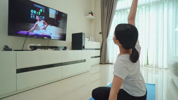 Asian beautiful young girl follow sport training video to exercise in house by watch online trainer. alt